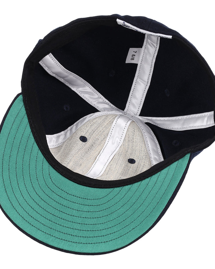An inside view of the EFF University of Nevada Wolf Pack Collegiate Wool Ballcap, showcasing navy blue wool, a green underbrim, white internal stitching, and a size tag labeled 7 5/8.