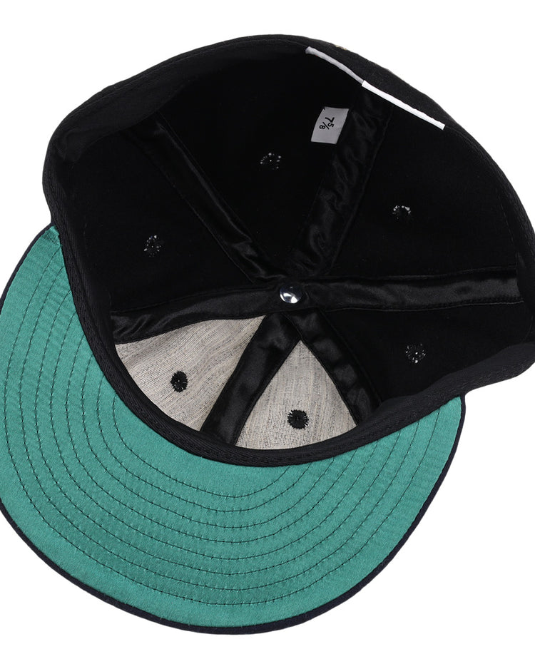 A look inside the black and green EFF New York Black Yankees Gilded Collection Ballcap shows stitching, inner seams, eyelets, and a 7 1/4 size tag—echoing classic Negro National League styles.