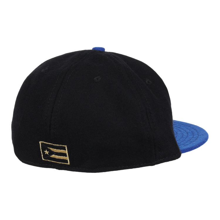 The EFF Santurce Cangrejeros Gilded Collection Ballcap in black features a blue brim and a gold-and-black flag patch on the left side, seen from the back—a stylish tribute to Puerto Rico League heritage.