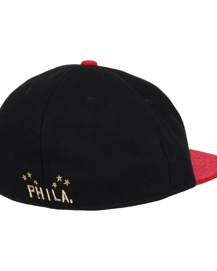 The EFF Philadelphia Stars Gilded Collection Ballcap is a vintage-style black cap with a red brim and top button, PHILA. on the front, and a gold embroidered logo with four stars on the back honoring the Negro National League.