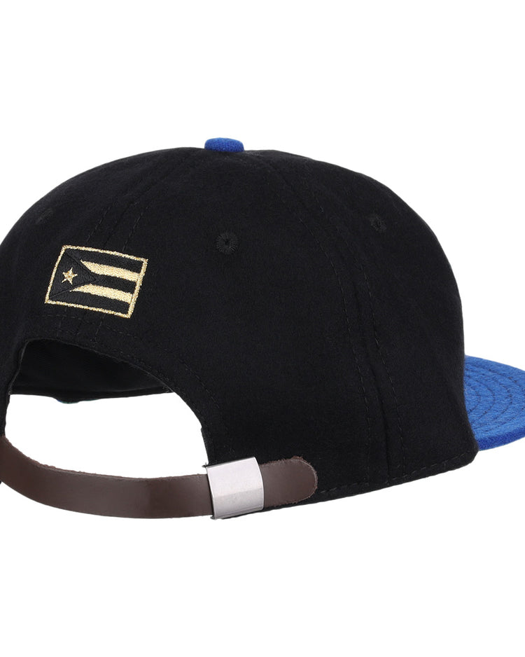 The EFF Santurce Cangrejeros Gilded Collection Ballcap is black with a blue brim, seen from the back. It has an adjustable brown strap and a small gold and white flag detail on the left side, inspired by Puerto Rico League heritage.