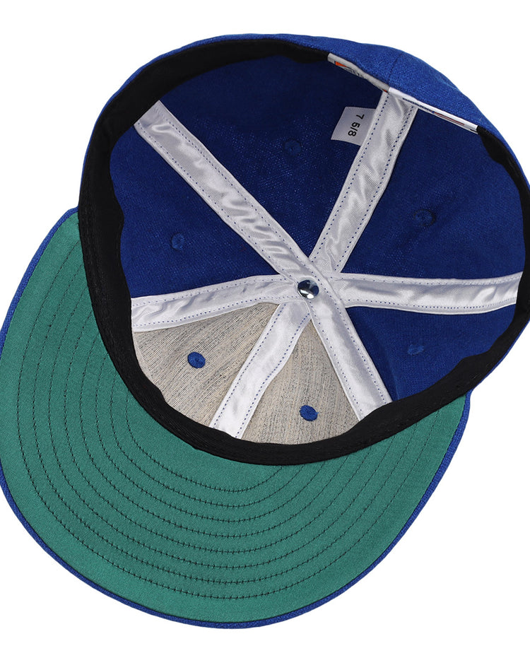 The image shows the inside view of an EFF Royal Ponciana Giants 1912 Vintage Ballcap in blue wool with a green brim, size tag 7 1/8, white and black lining, exposed stitching, and classic hotel league baseball styling.