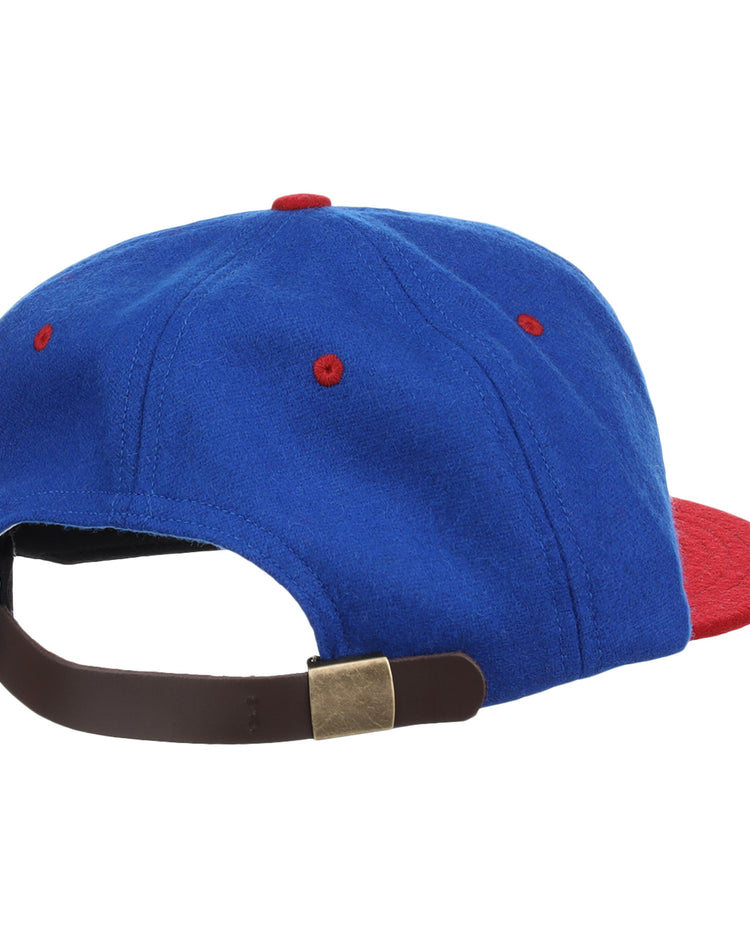 The EFF Nashville Cubs 1946 Vintage Ballcap, shown from the back, is blue with a red brim and red stitching accents. Made of vintage wool, it features an adjustable brown strap with a brass-colored buckle.