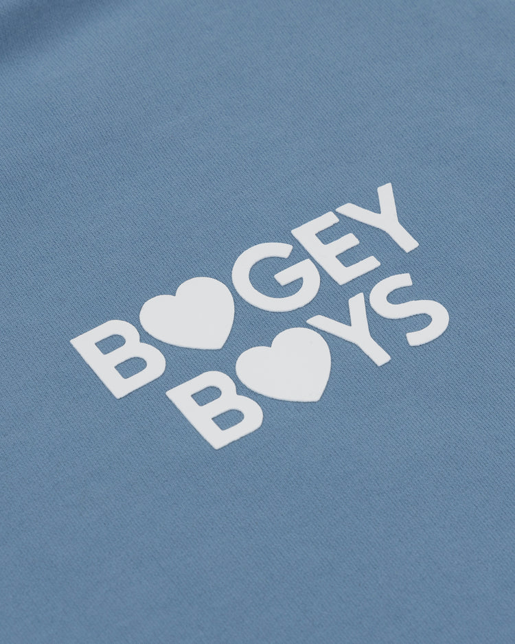The EFF Bogey Boys x EFF French Terry Hoodie features “BOGEY BOYS” in white with heart-shaped O’s, making this blue premium fleece a standout golf apparel piece.