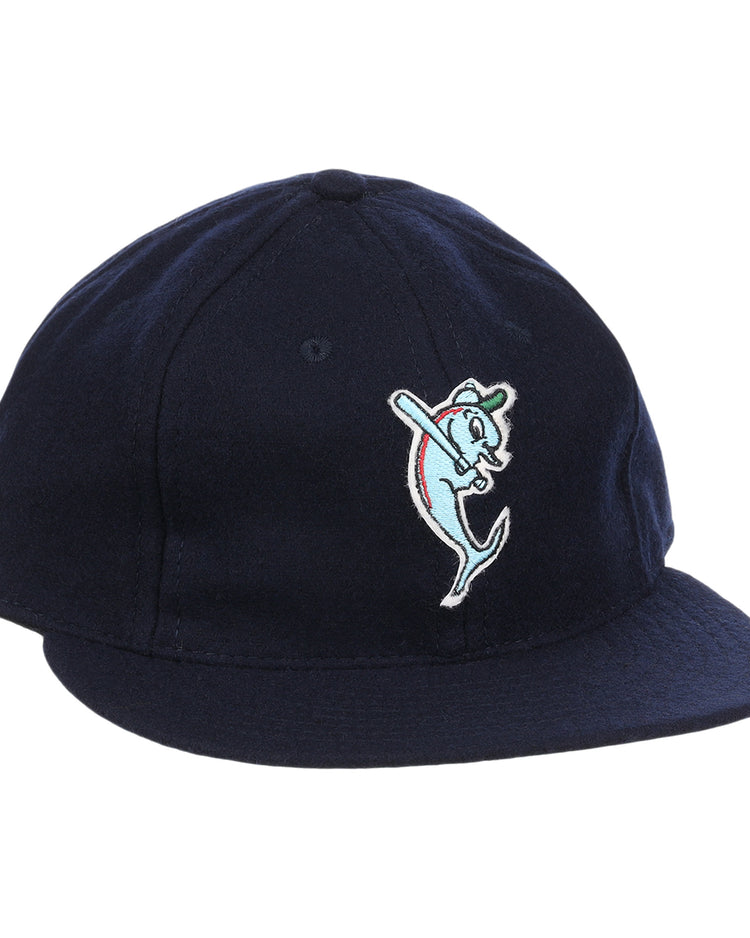 The EFF Tampa Tarpons Letterhead Wool Vintage Ballcap is a navy blue cap with a cartoon dolphin mascot in a green cap and red bat, inspired by Minor League baseball and the playful spirit of the Tampa Tarpons.