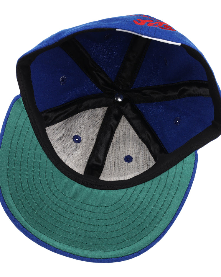 The EFF Columbus Jets Letterhead Wool Vintage Ballcap features a blue wool build, green brim, black inner seams, grey panels, and a white inner tag—capturing the classic style of vintage Minor League baseball caps.