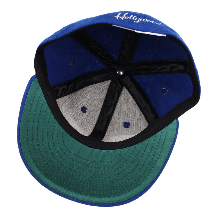 The image shows the inside of an EFF Hollywood Stars Letterhead Wool Vintage Ballcap, featuring a blue wool exterior, green underbrim, black banding, white stitching, and Hollywood partially visible on the inner front panel.
