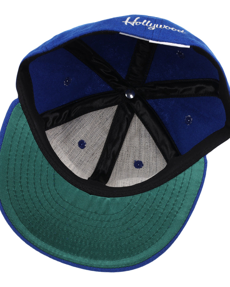 The image shows the inside of an EFF Hollywood Stars Letterhead Wool Vintage Ballcap, featuring a blue wool exterior, green underbrim, black banding, white stitching, and Hollywood partially visible on the inner front panel.