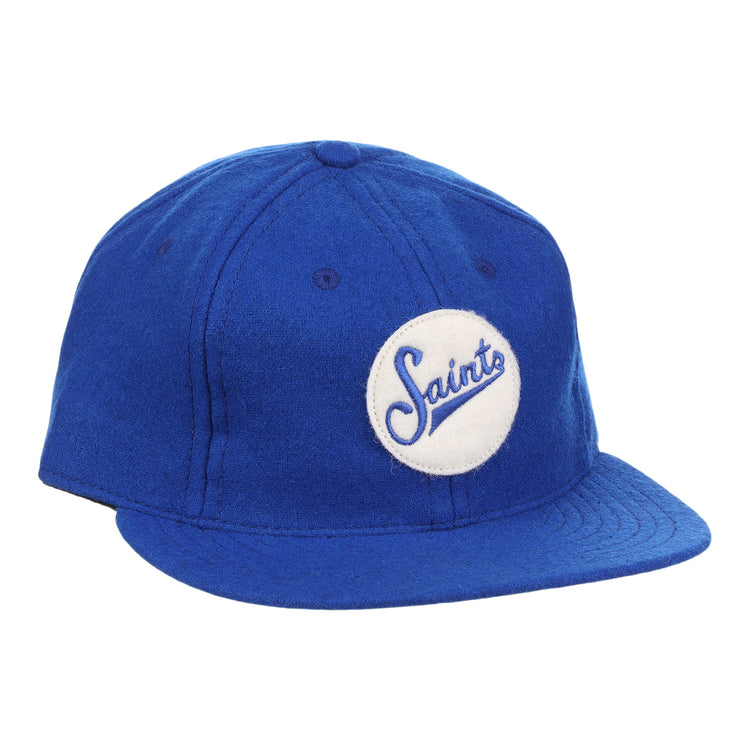 The EFF St. Paul Saints Letterhead Wool Vintage Ballcap is a blue wool cap with a flat brim and a white circular patch on the front that displays Saints in blue cursive, inspired by classic Minor League logos.