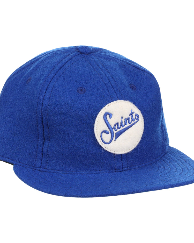 The EFF St. Paul Saints Letterhead Wool Vintage Ballcap is a blue wool cap with a flat brim and a white circular patch on the front that displays Saints in blue cursive, inspired by classic Minor League logos.