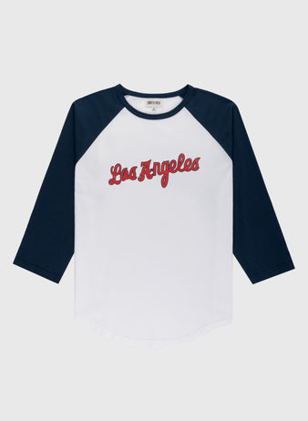 The Ebbets Field Los Angeles Angels (PCL) Vintage Baseball Tee is a white shirt with navy blue three-quarter sleeves and “Los Angeles” in red script, inspired by classic minor league team style, shown on a plain light gray background.