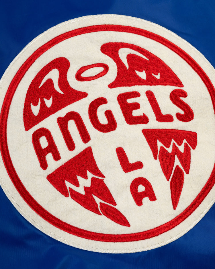 Close-up of a circular Los Angeles Angels (PCL) logo patch with red text and wing details on a white background, displayed on the blue Ebbets Field Satin Varsity Jacket. ANGELS and L A stand out, highlighting this classic jacket style.