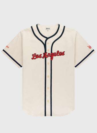The Ebbets Field Los Angeles Angels (PCL) Cotton Twill Jersey features a cream body, red Los Angeles script, navy trim on buttons and sleeves, and red LA on the left sleeve—ideal for any Pacific Coast League fan.