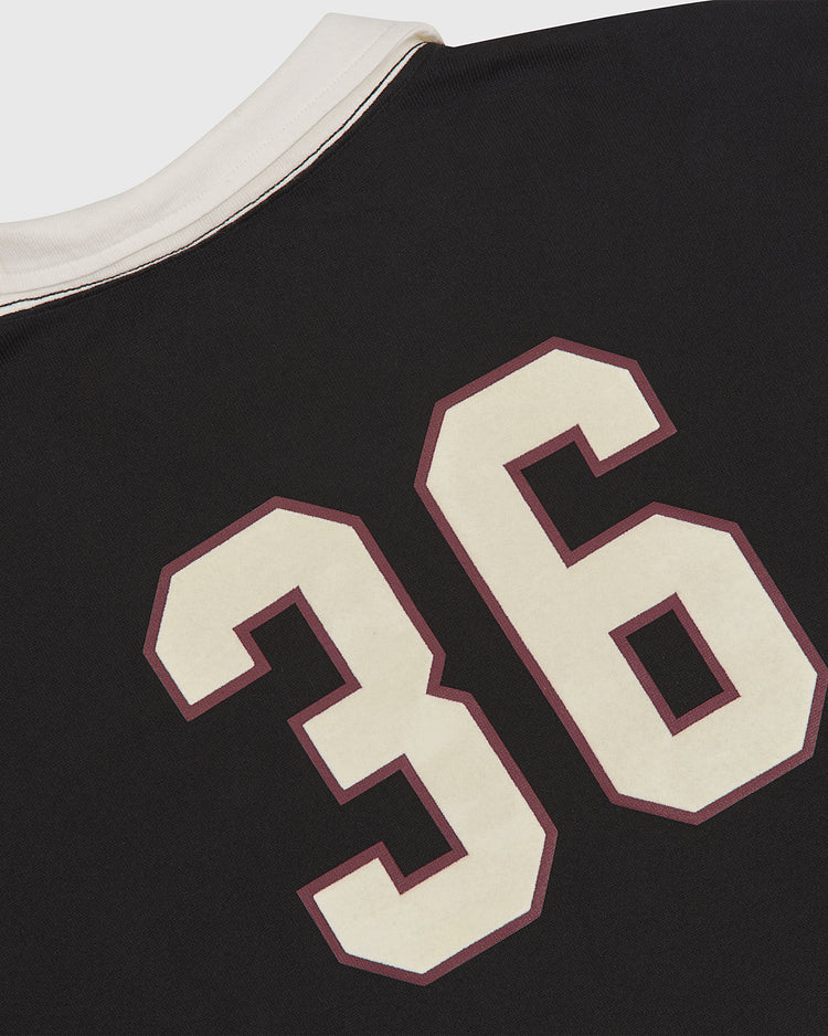 A close-up of the Ebbets Field Harvard University Vintage Soccer Goalie Jersey, featuring a black design with the number 36 in large white and maroon outlined print on the back near a white collar.