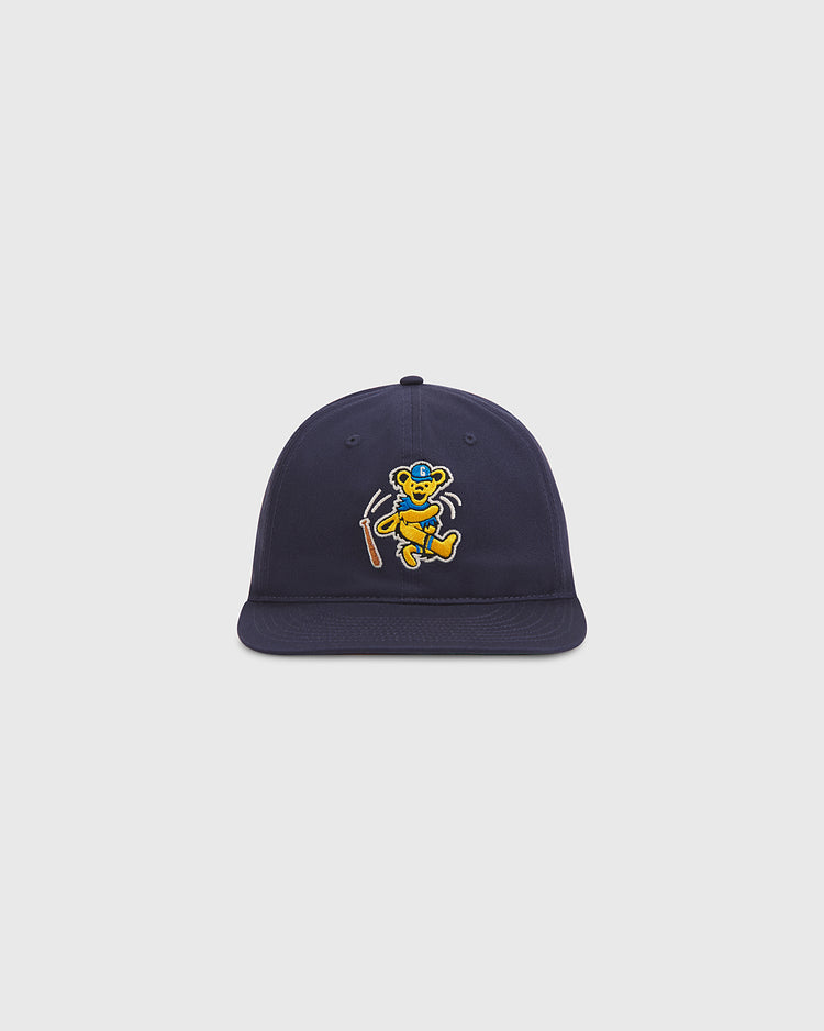 Show your playful spirit with the Grateful Dead Baseball Bear Cotton Twill Ballcap by Ebbets Field—this navy blue hat features an embroidered cartoon bear dancing and holding a walking stick on the front, set against a plain light gray background, making it an ideal choice for fans looking to add a whimsical twist to the classic ballcap.