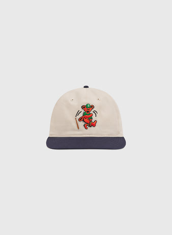 The Grateful Dead Baseball Bear Cotton Twill Ballcap by Ebbets Field features a cream-colored cotton twill design with a navy blue brim and an embroidered colorful dancing bear on the front—making it the perfect accessory for any fan.