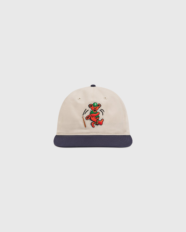The Grateful Dead Baseball Bear Cotton Twill Ballcap by Ebbets Field features a cream-colored cotton twill design with a navy blue brim and an embroidered colorful dancing bear on the front—making it the perfect accessory for any fan.