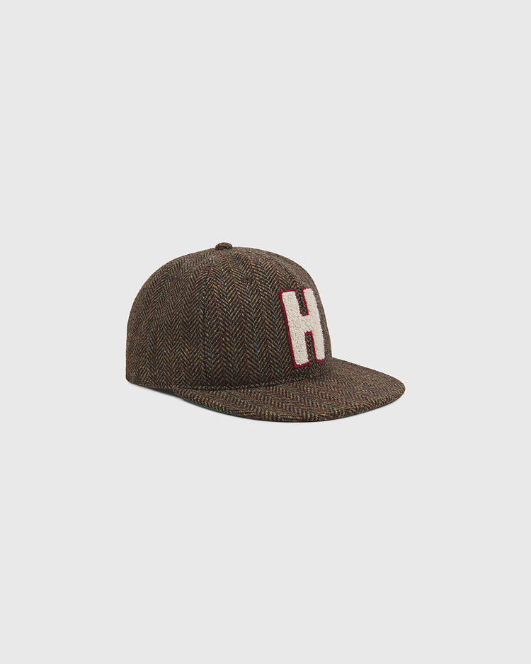 An Ebbets Field Harvard University Herringbone Wool Ballcap featuring a brown herringbone pattern and a prominent white “H” outlined in red on the front, displayed against a plain light gray background.
