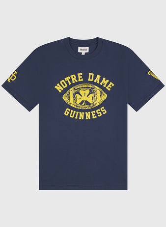 Show off your Irish heritage with the Ebbets Field Notre Dame X Guinness Short Sleeve Graphic Tee—a navy blue vintage shirt featuring bold yellow text, a football graphic with a shamrock, and striking yellow logos on both sleeves.