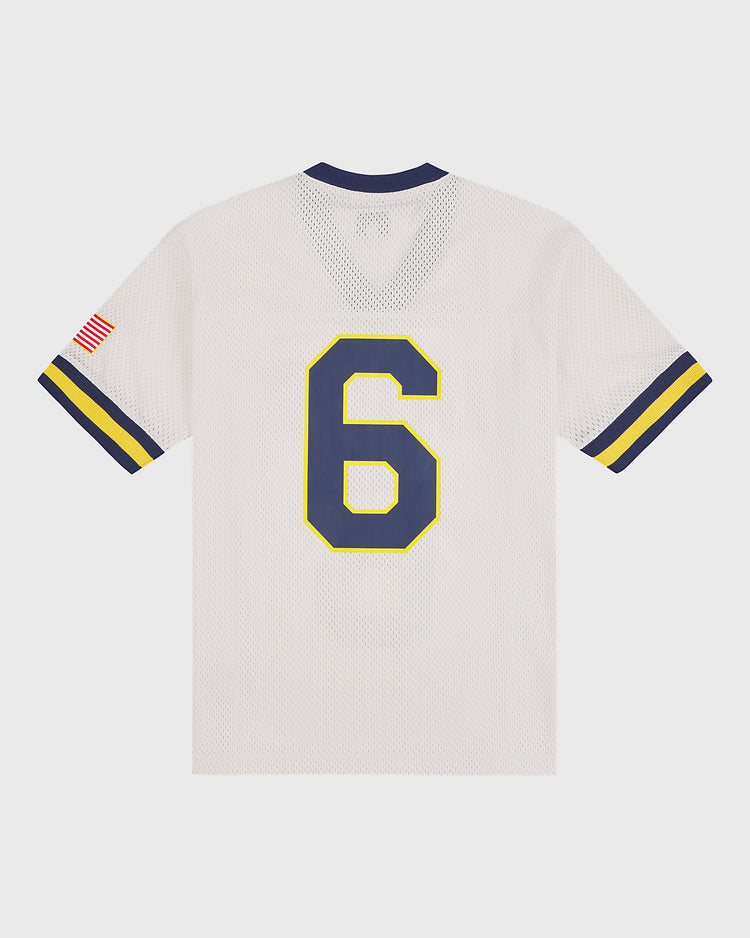 A classic US Naval Academy Mesh Football Jersey by Ebbets Field, this white jersey showcases blue and yellow stripes on the sleeves, an American flag patch on the right sleeve, and a bold blue number 6 outlined in yellow on the back.