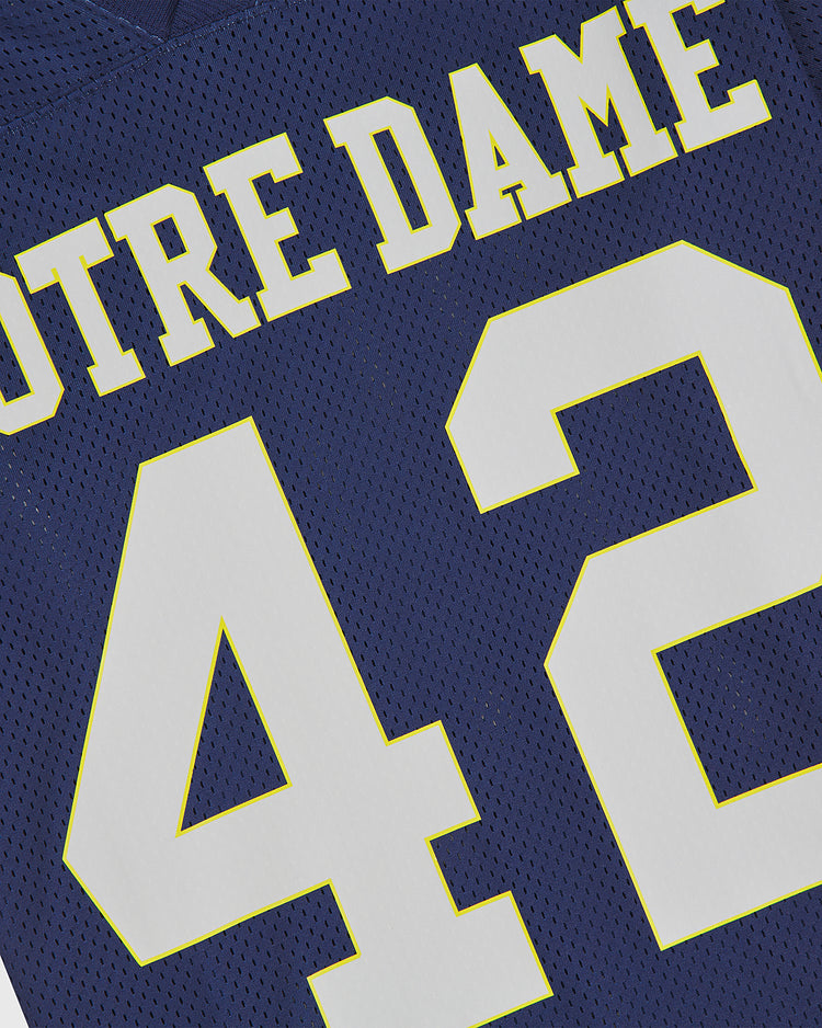 Close-up of the Ebbets Field Notre Dame Mesh Football Jersey in navy blue, featuring “NOTRE DAME” in yellow-white letters and the white number 42 outlined in yellow—a classic look inspired by the Fighting Irish football tradition.