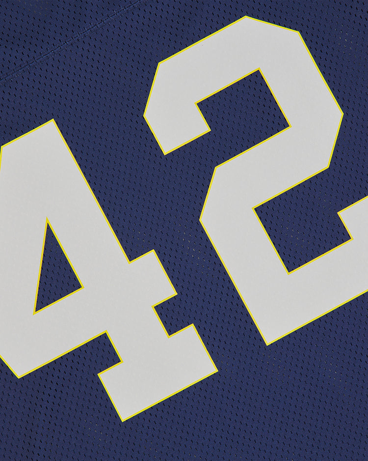 Close-up of the Ebbets Field Notre Dame Mesh Football Jersey in blue, featuring large white number 42 outlined in yellow. The textured mesh fabric and detailed stitching capture the timeless style of classic Fighting Irish football.