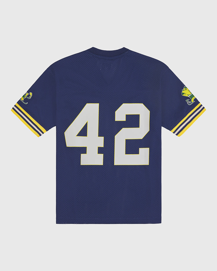 Introducing the Ebbets Field Notre Dame Mesh Football Jersey—a navy blue vintage-inspired jersey featuring yellow and white sleeve stripes, a yellow logo patch on each sleeve, and bold white number 42 on the back, capturing the classic spirit of Notre Dame football tradition.