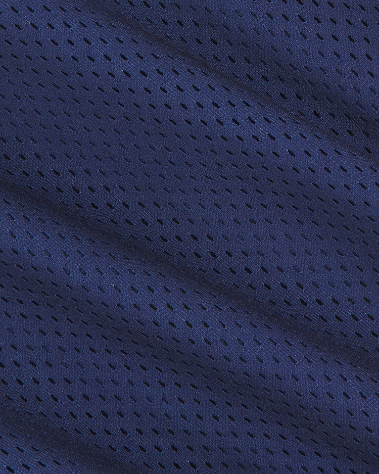 Close-up of the Ebbets Field Notre Dame Mesh Football Jersey, showing dark blue mesh fabric with small, evenly spaced holes and gentle folds forming diagonal lines, reminiscent of a classic vintage style.