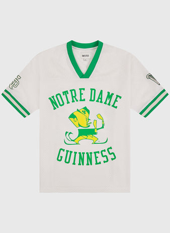 Show your Irish pride with the Notre Dame X Guinness Mesh Football Jersey by Ebbets Field. This white mesh sports jersey features green trim, a leprechaun mascot holding a beer, and the words “Notre Dame Guinness” in green across the front. Designed with classic symbols on both sleeves, this vintage-inspired football jersey is perfect for fans who appreciate tradition and want to celebrate their Irish heritage in authentic Ebbets Field style.