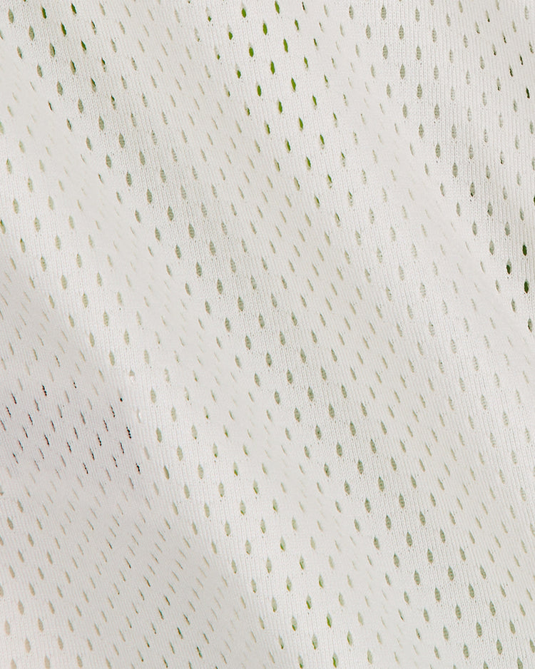 Crafted by Ebbets Field, the Notre Dame X Guinness Mesh Football Jersey showcases a lightweight white fabric with a subtle greenish tint and features diagonally arranged, evenly spaced perforations that create a breathable mesh texture. This design pays homage to classic craftsmanship and celebrates Irish heritage, reminiscent of vintage football jerseys.
