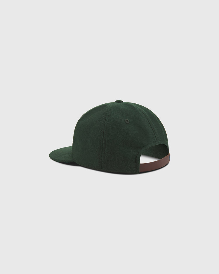 A Notre Dame X Guinness Wool Ballcap by Ebbets Field is pictured from the back, showcasing its dark green wool material, adjustable brown strap, and classic button on top, set against a plain light gray background.