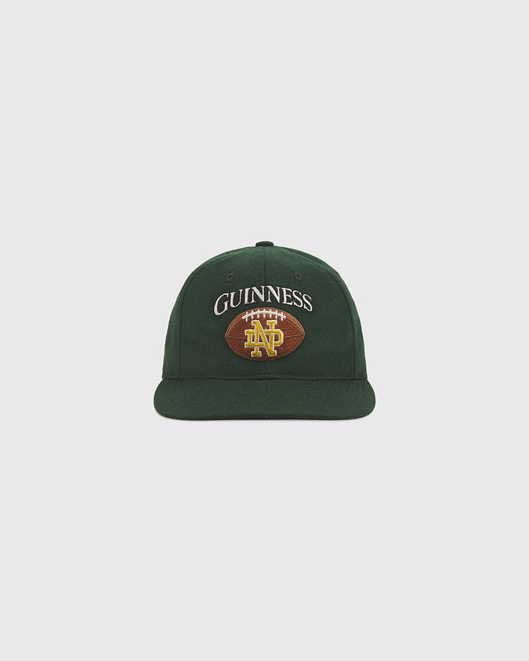 Celebrate Notre Dame pride with the Ebbets Field Notre Dame X Guinness Wool Ballcap—a green wool cap featuring “GUINNESS” embroidered above a football design with bold yellow ND letters on the front.