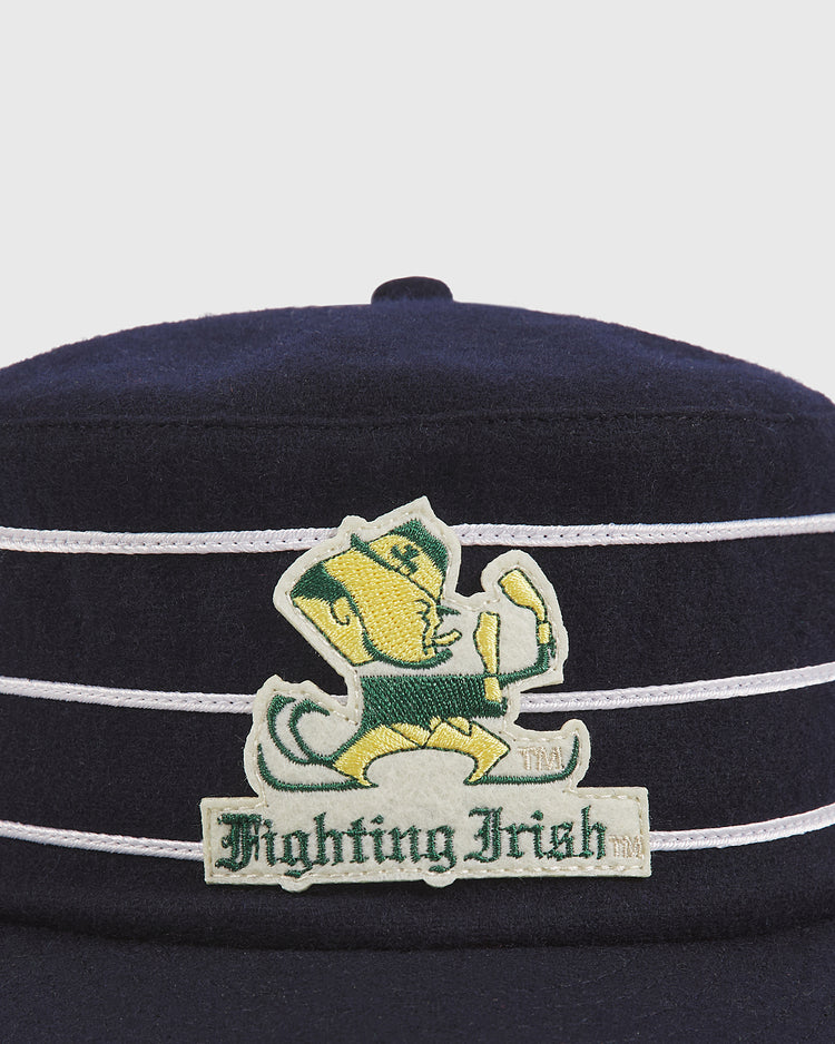 Ebbets Field Notre Dame Pillbox Cap in navy blue with white stripes, featuring the Fighting Irish leprechaun logo and “Fighting Irish” text on the front.