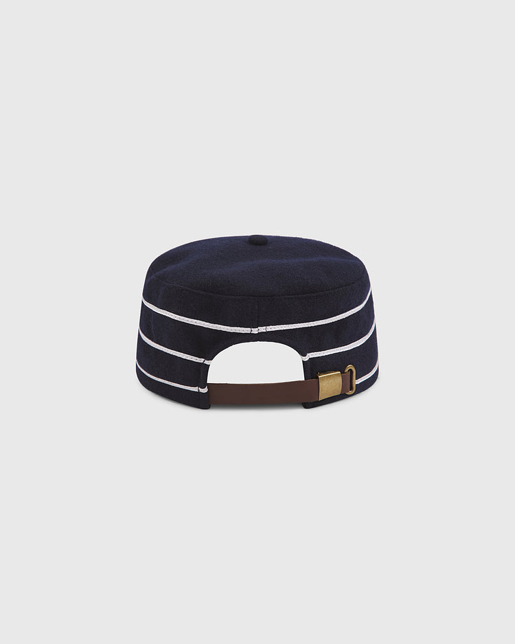 The Ebbets Field Notre Dame Pillbox Cap is shown from the back, featuring navy blue fabric with white horizontal stripes. A brown adjustable strap with a gold buckle is visible, and the cap rests against a plain light gray background.