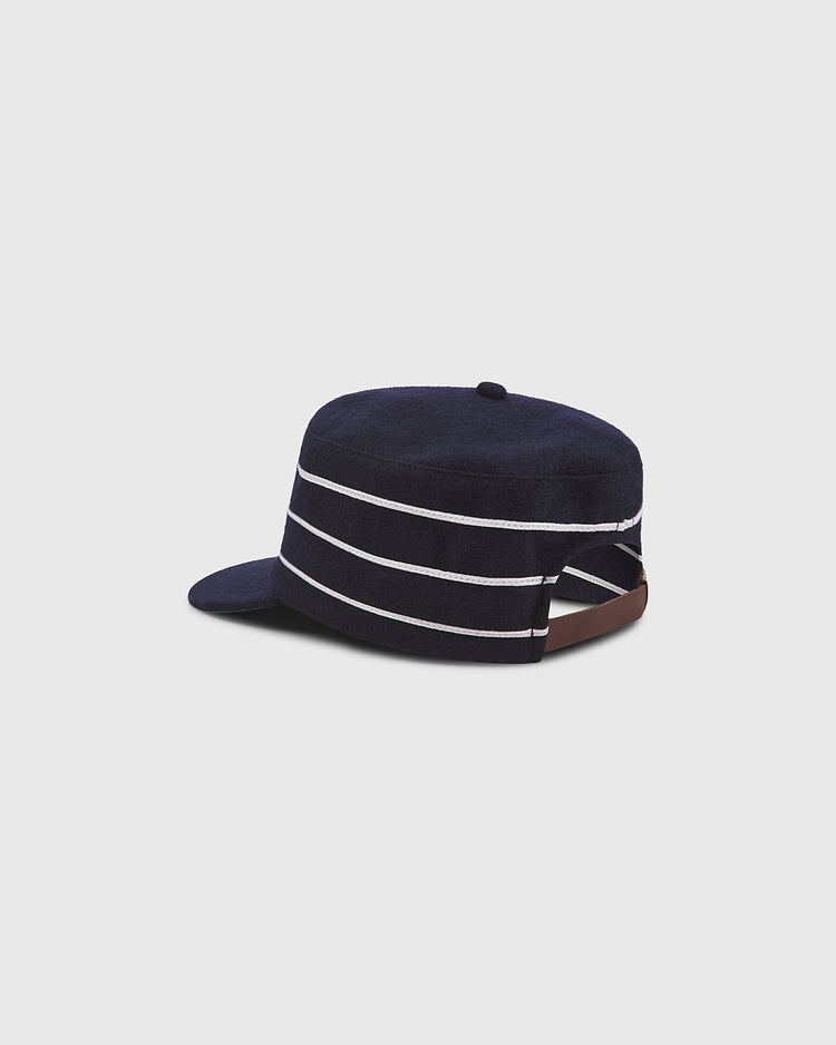 The Ebbets Field Notre Dame Pillbox Cap features a navy blue design with three white horizontal stripes, a flat brim, and an adjustable brown strap at the back, displayed against a plain light gray background.