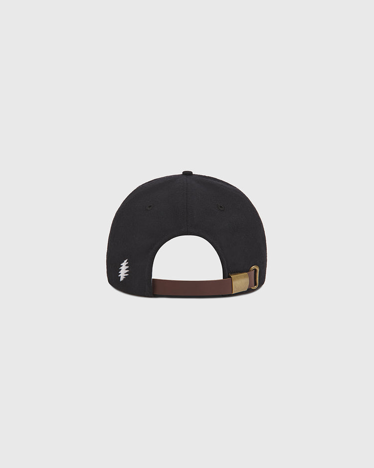 The Grateful Dead Stealie Wool Ballcap by Ebbets Field is shown from the back, featuring a black wool design with an adjustable brown strap and brass buckle, along with a small white embroidered detail on the left side.