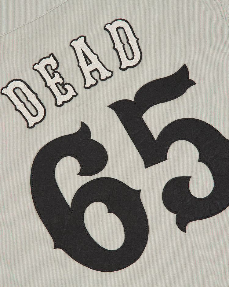 The Grateful Dead Cotton Twill Button-Up Baseball Jersey by Ebbets Field features the word DEAD above bold, stylized black numbers 65 on a light cotton twill background, evoking the classic Grateful Dead jersey designs and iconic psychedelic band apparel.