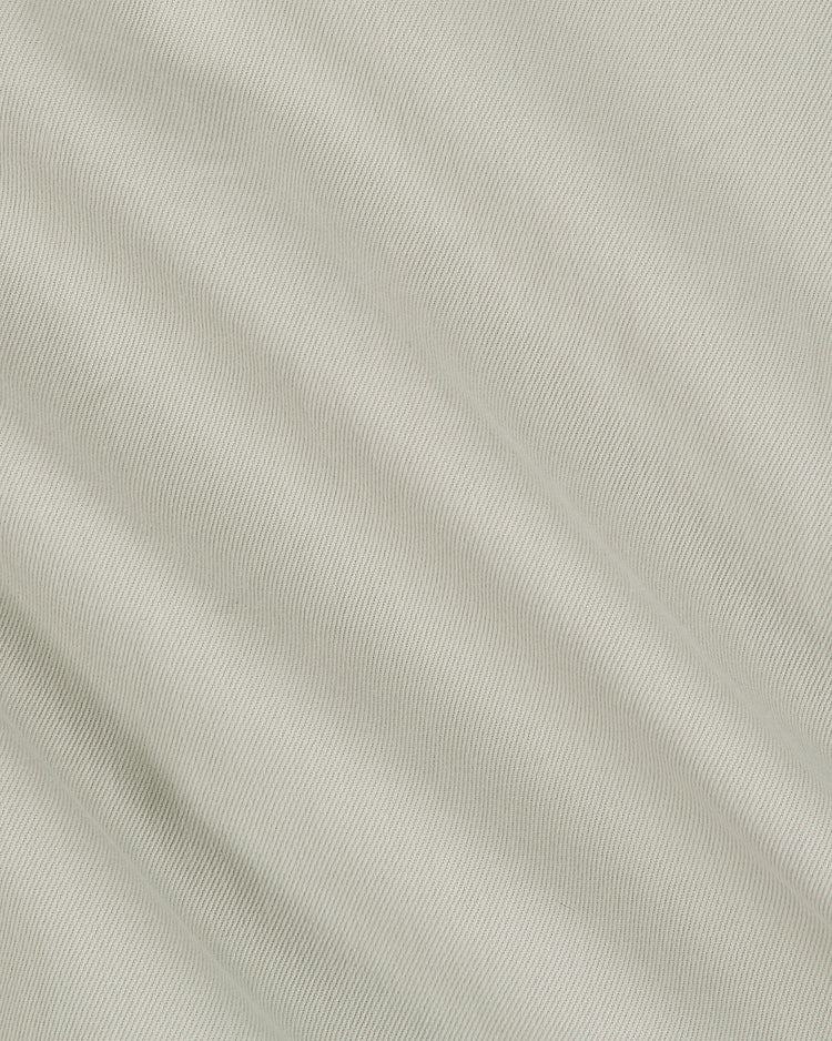 Close-up of the Grateful Dead Cotton Twill Button-Up Baseball Jersey by Ebbets Field, featuring light beige cotton twill fabric with a subtle diagonal ribbed texture and gentle folds that create soft shadows and highlights across the surface—a perfect choice for fans of psychedelic band apparel.