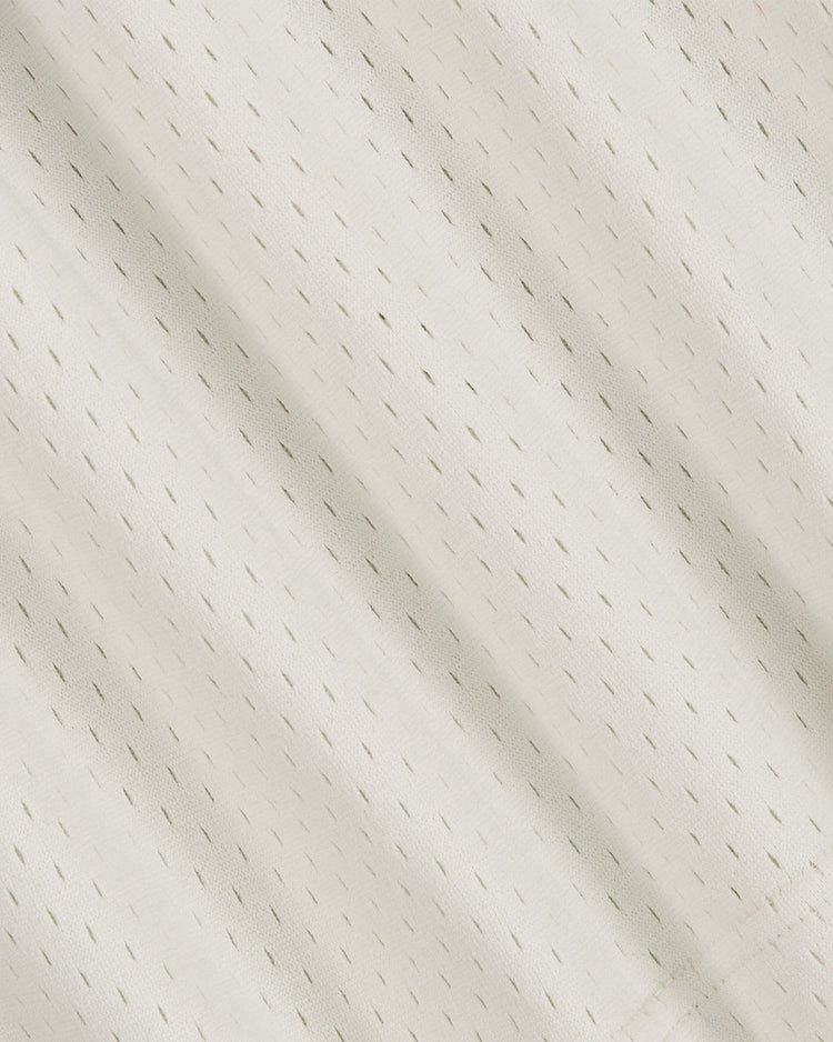 Close-up of light beige mesh fabric from the Ebbets Field Penn State University Mesh Football Jersey, featuring small, evenly spaced vertical perforations and subtle diagonal shadows that evoke a vintage aesthetic.