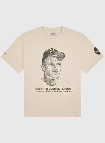 Celebrate an iconic moment in baseball history with The Clemente Museum x Ebbets Field Short Sleeve Graphic T-Shirt by Ebbets Field. This beige tee features a sketched portrait of a baseball player and the text “Roberto Clemente Night, July 24, 1970 - Three Rivers Stadium” below, along with a commemorative patch on the left sleeve. A must-have graphic tee for any Roberto Clemente or Pittsburgh Pirates fan.