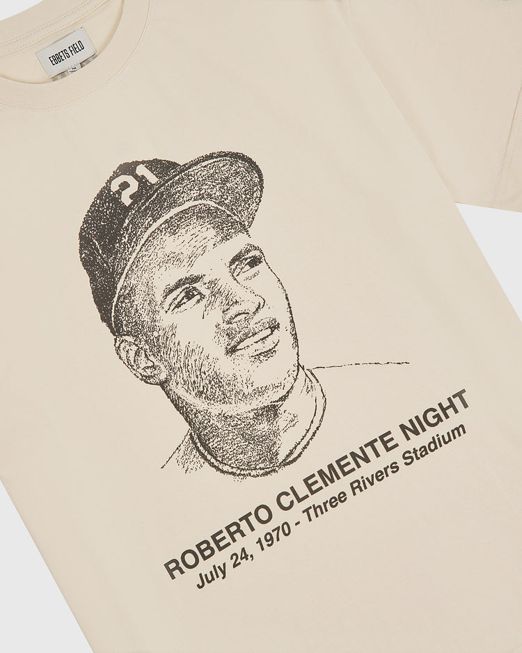 The Ebbets Field “The Clemente Museum x Ebbets Field Short Sleeve Graphic T-Shirt” is a cream-colored tee featuring a sketched portrait of a baseball player and the text “ROBERTO CLEMENTE NIGHT July 24, 1970 - Three Rivers Stadium.” This Pittsburgh Pirates shirt is the perfect tribute for fans seeking a classic Roberto Clemente graphic tee.
