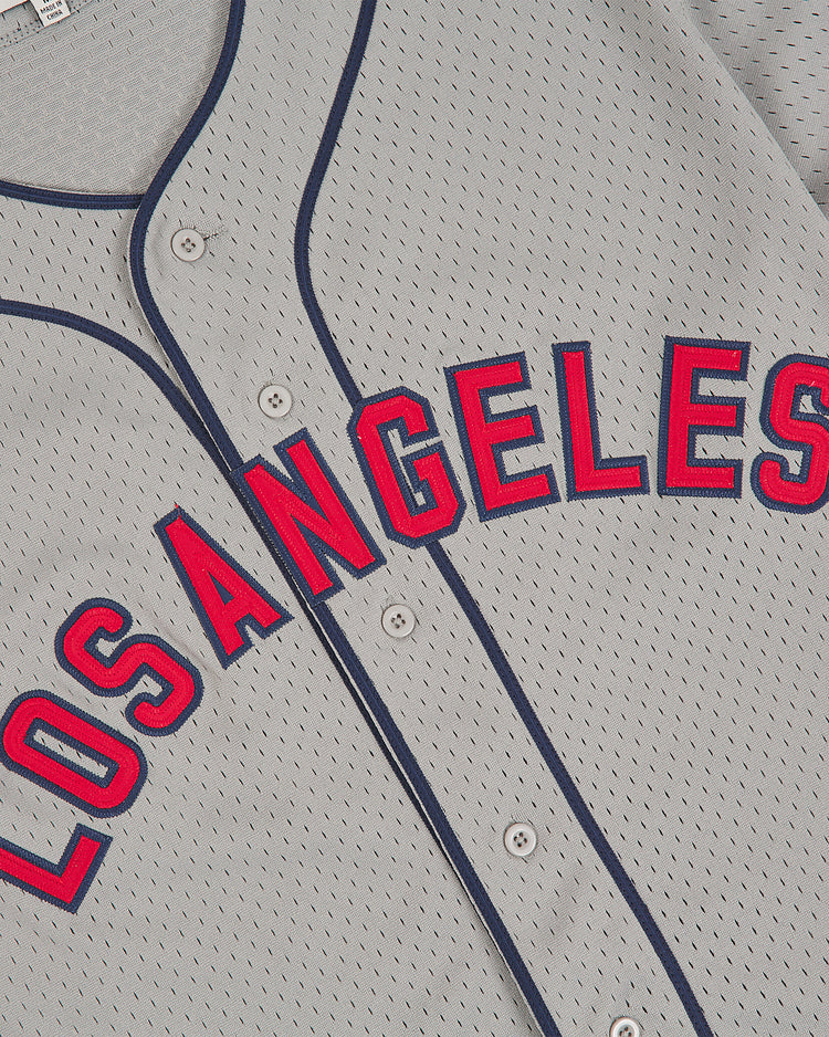 The Ebbets Field Los Angeles (PCL) 1942 Mesh Button Up Road Jersey features a gray design with “Los Angeles” in red letters outlined in blue across the front, complete with blue piping along the buttons and collar.