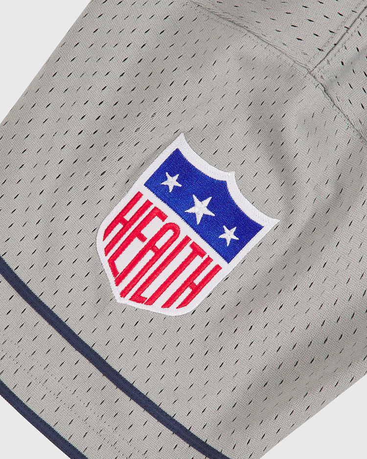 A gray Los Angeles (PCL) 1942 Mesh Button Up Road Jersey by Ebbets Field features a shield logo with three white stars above blue and red stripes, containing the word HEALTH in bold letters.