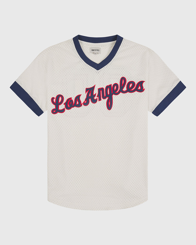 White mesh Los Angeles Angels (PCL) 1957 V-neck home jersey by Ebbets Field, featuring a navy blue V-neck collar and sleeve trim, with “Los Angeles” in red cursive script outlined in navy. Ebbets Field brand label on hem.