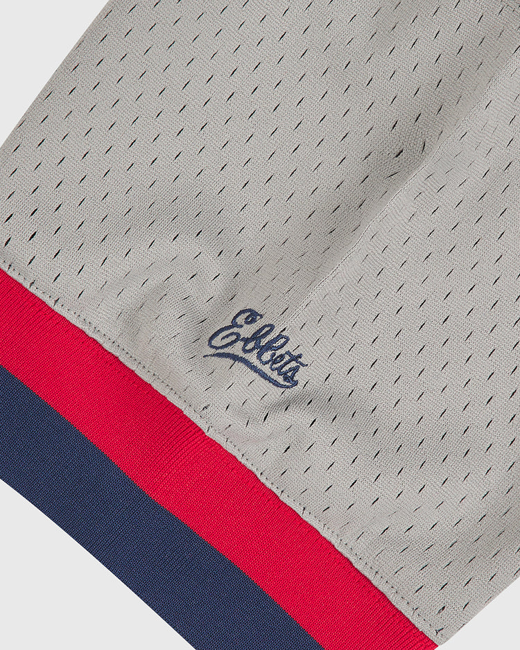Close-up of the Oakland Oaks 1948 Mesh V-Neck Road Jersey by Ebbets Field, showcasing gray mesh fabric with a navy script logo and red and navy stripe trim along the hem.