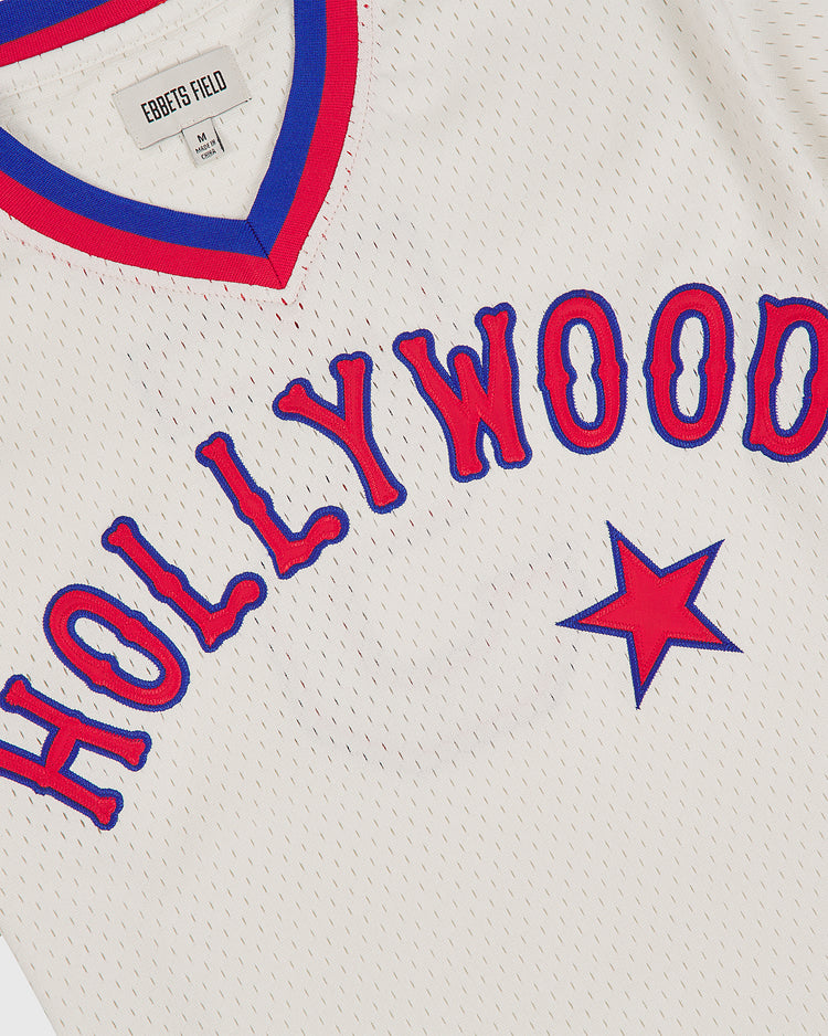 The Hollywood Stars 1940 Mesh V-Neck Home Jersey by Ebbets Field is a white mesh jersey with red and blue trim, featuring the word “HOLLYWOOD” in bold blue letters outlined in red with a red star beneath.