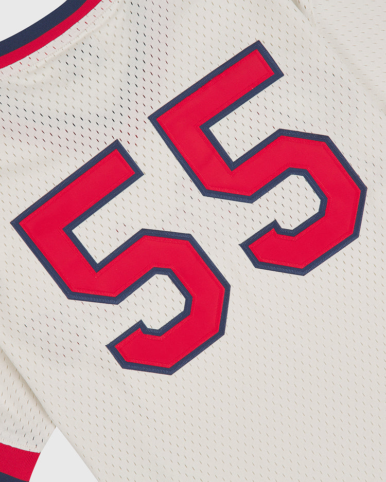 The Seattle Rainiers 1955 Mesh V-Neck Home Jersey by Ebbets Field is a white sports jersey with a perforated mesh texture and features a large red and blue outlined number 55. A section of the red and blue collar is visible at the top.