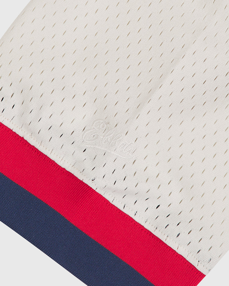 Ebbets Field’s Seattle Rainiers 1955 Mesh V-Neck Home Jersey features a white mesh fabric with small perforations, subtle embroidered lettering, and is finished with red and navy blue stripes at the edge.