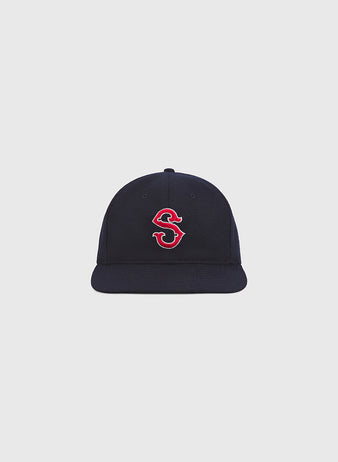 An authentic Seattle Rainiers 1950 wool ballcap by Ebbets Field, featuring a navy blue design and a red and white embroidered “S” on the front, is displayed against a plain light gray background.