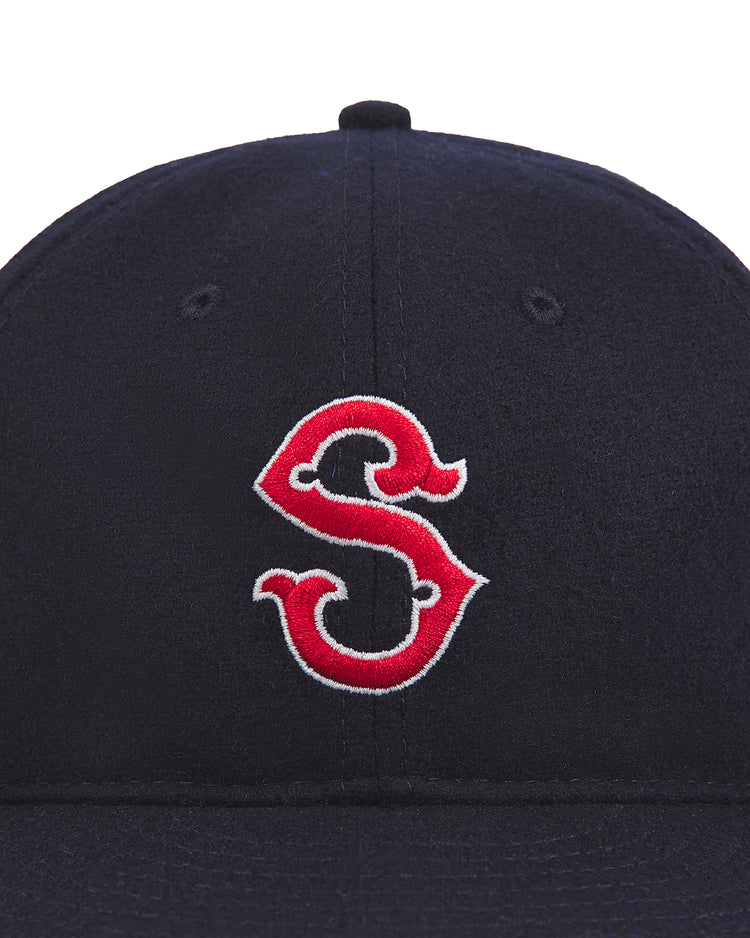 The Seattle Rainiers 1950 Authentic Wool Ballcap by Ebbets Field is a navy blue hat inspired by the 1950 Seattle Rainiers, featuring a bold red and white embroidered “S” on the front for a classic vintage baseball look.